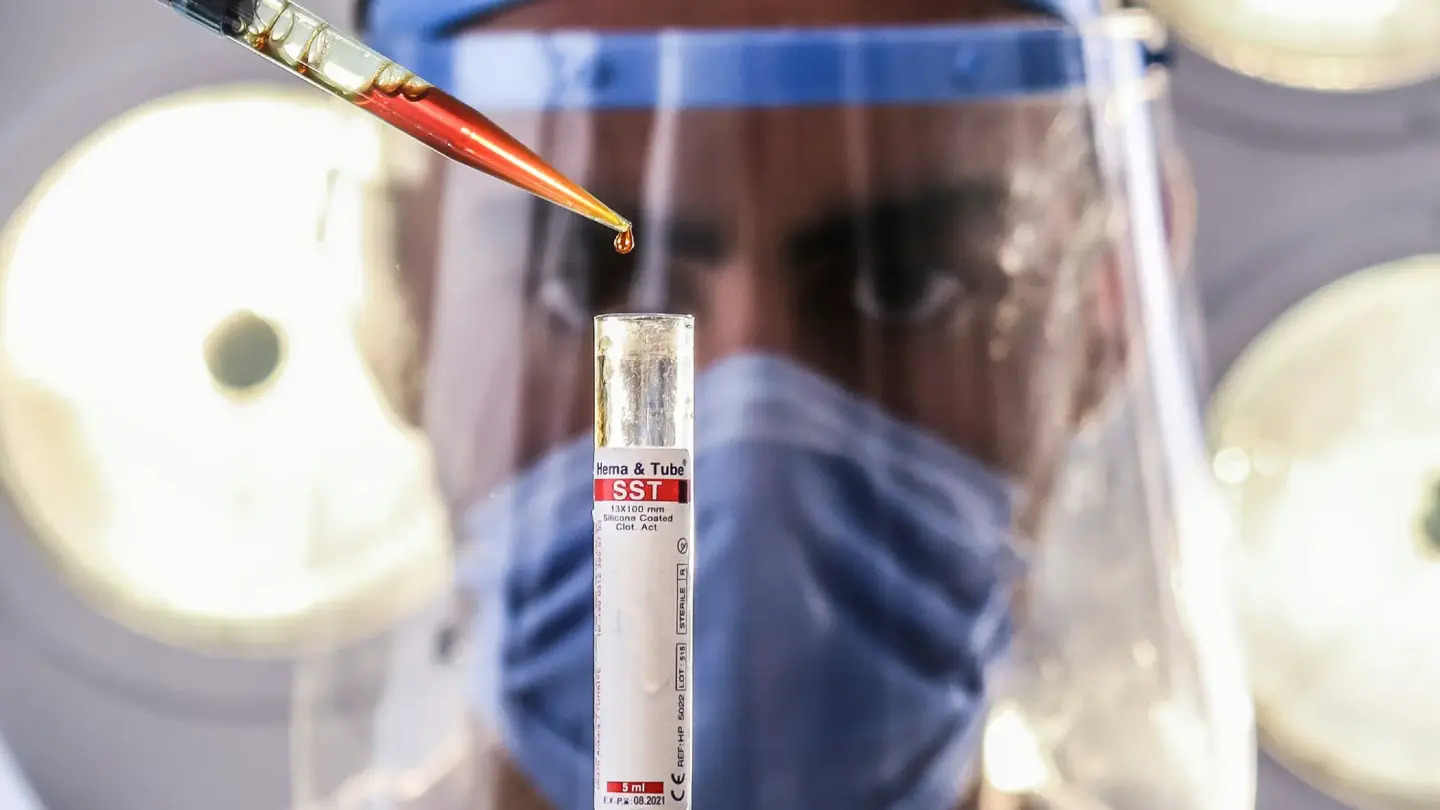 Scientist dropping solution into test tube Biomarker Testing Options